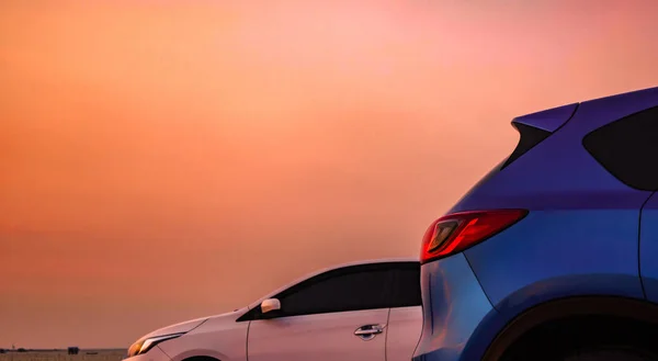 Mașină SUV compactă albastră cu design sportiv și modern parcată pe șosea de beton lângă mare la apusul soarelui. Maşină ecologică albă. Tehnologie ecologică. Conceptul de succes în afaceri . — Fotografie, imagine de stoc