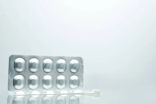 Confezione in blister di alluminio argento contenente 2 compresse bianche su sfondo bianco con ombre e spazio per la copia del testo. Concetto di imballaggio farmaceutico e stoccaggio di medicinali — Foto Stock