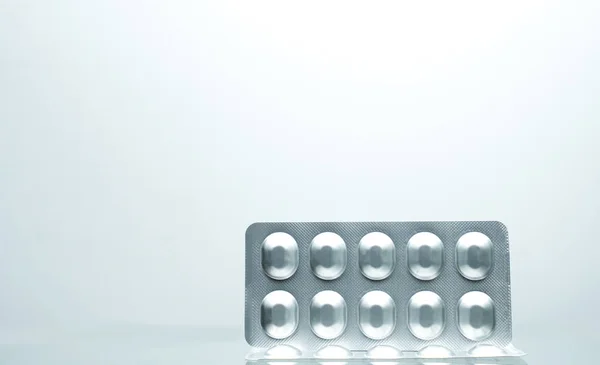 Серебряная алюминиевая фольга пузырь пакет таблеток на белом фоне с тенями и копировать пространство для текста. Концепция хранения фармацевтической упаковки и медикаментов — стоковое фото