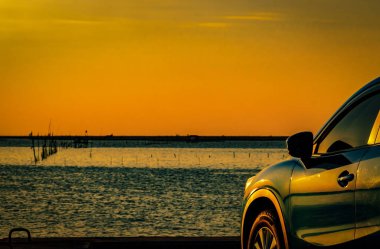 Mavi kompakt Suv araç spor ve modern tasarımı ile deniz kenarında beton yol üzerinde günbatımında Park. Çevre dostu teknoloji. İş başarı kavramı.