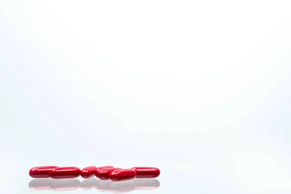 Rode capsule pillen geïsoleerd op een witte achtergrond met schaduwen en kopie ruimte voor tekst. Vitamine en supplement voor zwangerschap en ouderen. — Stockfoto