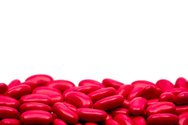 Macro detalle de inyección de píldoras recubiertas de azúcar en forma de riñón rojo sobre fondo blanco con espacio de copia para el texto — Foto de Stock