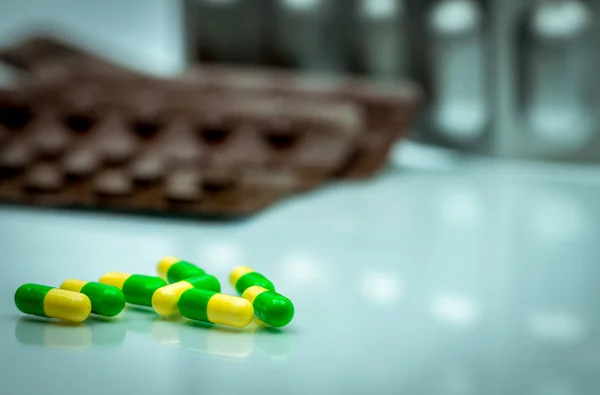Green, yellow tramadol capsule pills on blurred blister pack background with copy space. Cancer pain management. Opioid analgesics. Drug abuse in teenage in Thailand. — Stock Photo, Image