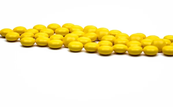 Detail tembakan makro dari pil tablet berlapis gula bundar kuning pada latar belakang putih dengan ruang fotokopi untuk teks . — Stok Foto