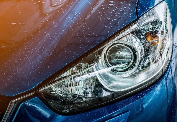 Blu compatto SUV auto con sport e design moderno sono lavaggio con acqua. Servizio di assistenza auto concetto di business. Auto coperta con gocce d'acqua dopo la pulizia con spruzzi d'acqua ad alta pressione — Foto Stock
