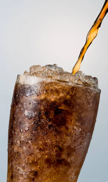 Closeup de refrigerante derramando em vidro com cubos de gelo triturado isolado em fundo branco com espaço de cópia. Há uma gota de água na superfície de vidro transparente . — Fotografia de Stock