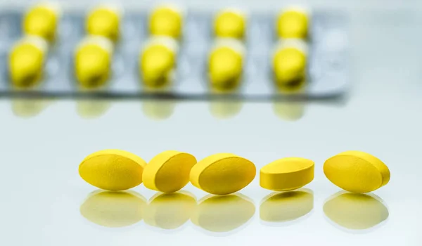 Detalle de Macro shot de comprimidos ovalados amarillos sobre fondo blanco con blisters como fondo — Foto de Stock