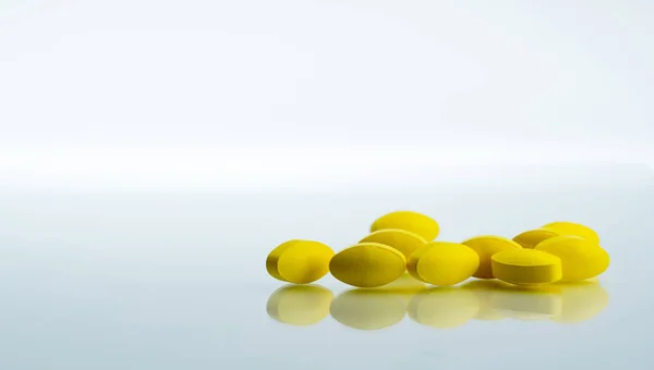 コピーのテキストのための領域の白い背景の上の黄色の楕円形タブレット錠剤の山。軽度中等度の疼痛管理に。痛み止め。薬は、高発熱を和らげるため. — ストック写真