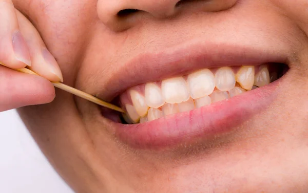 Asiatische Frau putzt ihre Zähne von Lebensmitteln, die ihre Zähne mit einem Zahnstocher aus Bambusholz nach dem Frühstück, Mittagessen, Abendessen stecken. persönliche Zahnpflege im asiatischen Stil. Konzept für Zahngesundheit und Mundgeruch. — Stockfoto