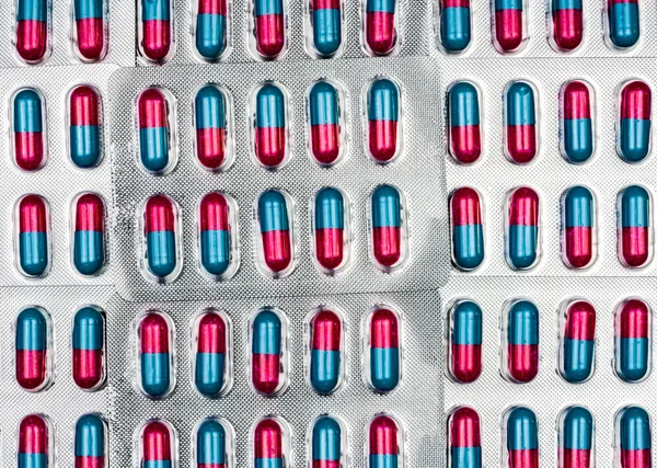 Colorido de azul, cápsula rosa con gránulos en píldoras laterales. Pastillas en blíster sobre fondo blanco con espacio. Forma farmacéutica de la dosificación y embalaje.Medicina antifúngica . — Foto de Stock