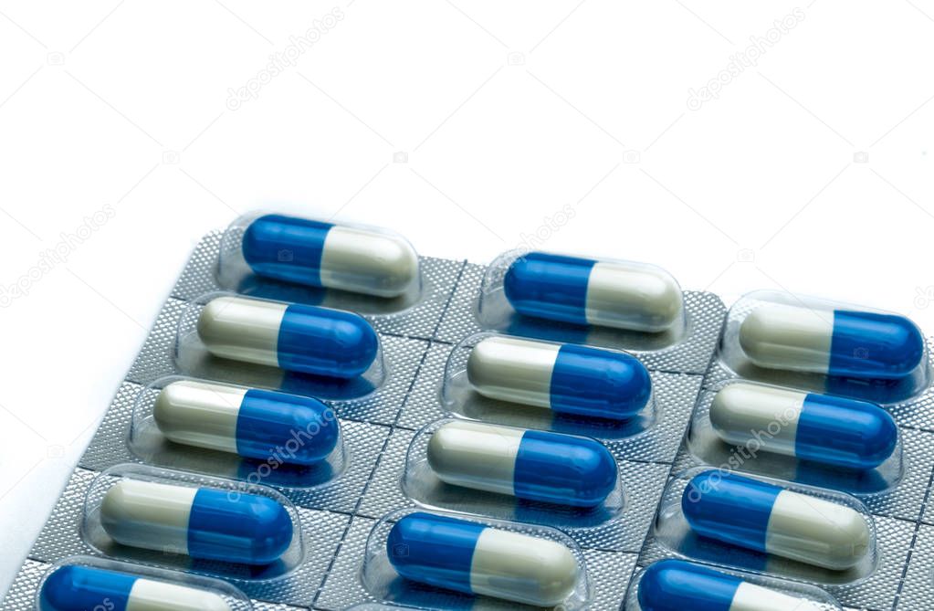 Blue-white capsule pills in blister pack isolated on white background with copy space for text. Antibiotics drug resistance and antimicrobial drug use with reasonable concept. Global healthcare.