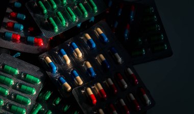 Vakumlu Ambalaj koyu arka plan üzerinde renkli kapsül hap yığını. Uyuşturucu politikası ve bütçeler. Antibiyotik ilaç ile makul kullanın. Antibiyotik ilaç direnci kavramı. Kontrendikasyonlar hap.