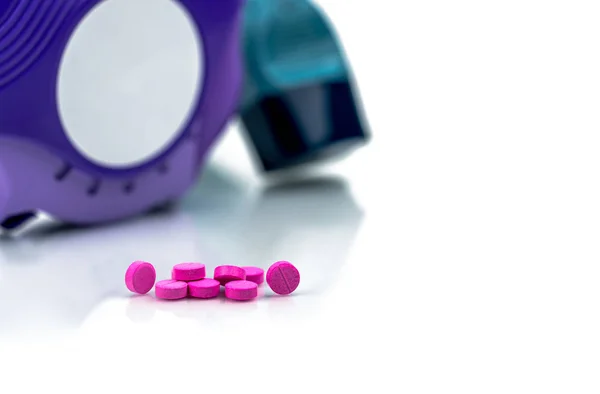 Mucchio di rotondo rosa piccole compresse pillole su sfondo sfocato di inalatore di asma un accualatore. Medicina broncodilatatrice per il trattamento dell'asma negli adulti. Pillole di Salbutamolo (Albuterolo) compresse . — Foto Stock
