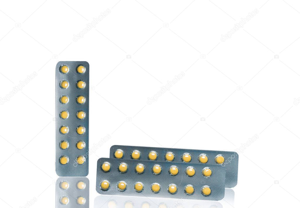Small round light yellow enteric-coated tablet pills in blister pack isolated on white background with copy space. Medicine for treatment gastric ulcer (stomach ulcer) or GERD.