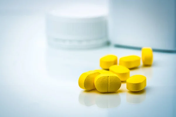 Mucchio di compresse gialle pillole su sfondo sfocato di bottiglia pillole di plastica con spazio copia. Ibuprofene per alleviare il dolore, mal di testa, febbre alta e anti-infiammatori. Primo piano di pillole antidolorifici capsule . — Foto Stock