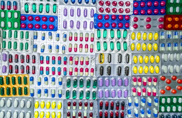 彩色药丸和胶囊药丸在水泡包装的顶视图排列精美的图案。制药工业概念。全框药丸背景。全球药品 — 图库照片