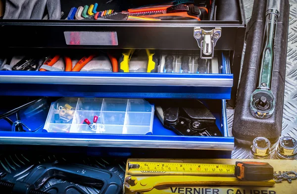 Close-up van hulpmiddelen in vak op geruite plaat achtergrond in werkplaats. Service tools set. Huis bouwen en elektrische gereedschappen. Loodgieter handgereedschap. Technicus apparatuur voor reparatiewerk. — Stockfoto