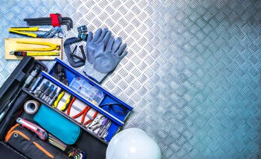 Damalı plaka arka plan atölye üzerinde üstten görünüm araçları kutusunu ve kask. Servis araçları seti. Ev inşa ve elektrikli araçlar. Tesisatçı el aletleri. Onarım işleri için teknisyen donatım.