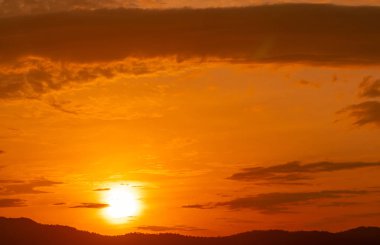 Güzel turuncu günbatımı gökyüzü ve orman üzerindeki bulutlar. Alacakaranlık gökyüzü. Doğa geçmişi. Muhteşem bir manzara. Huzurlu ve soyut bir arka plan. Akşamları büyük altın güneş. Bulutlar alacakaranlıkta.