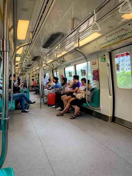 新加坡- 2019年5月20日：乘坐Mrt列车的游客。 亚洲人在火车上使用智能手机。 新加坡的公共交通。 带着行李的游客由Mrt到城里旅行. 亚洲内地列车. — 图库照片