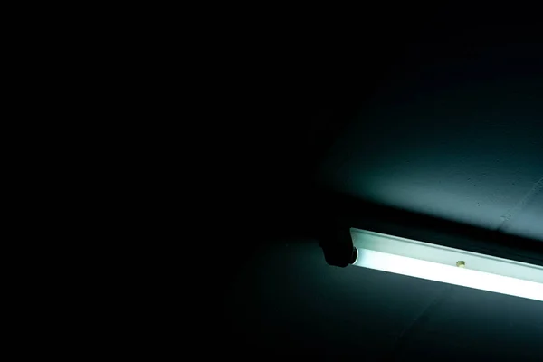 Открытая светодиодная лампа на темном фоне. Светодиодный люминесцентный фонарь. Осветительное оборудование. Интерьер светильника. Энергосберегающие лампочки установлены на потолке в помещении жилого бетонного здания . — стоковое фото
