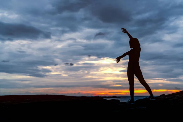 Silhouette woman workout in the morning at stone beach with beautiful sunrise sky. Fit woman stretching body before workout. Exercise for healthy lifestyle. Out door workout. Nature landscape. Freedom — Stock Photo, Image