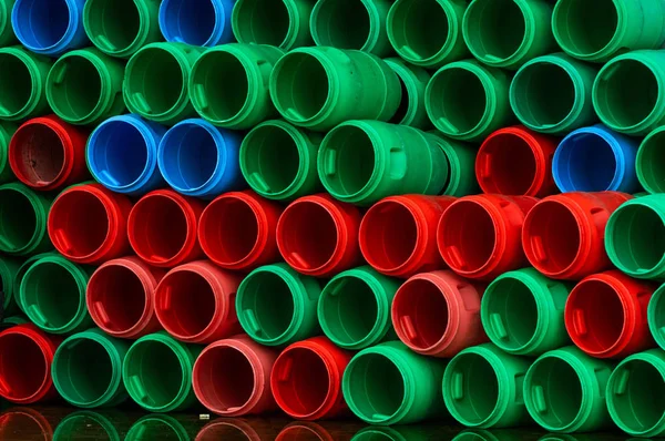 Used plastic barrels. Blue, green, and red plastic drum. Stacked of empty tank in food factory waiting for recycle and reuse. Container of raw material in food manufacturing industry. Old plastic drum