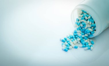 Mavi-beyaz antibiyotik kapsül hapı ve kapsül hapları şişesi. Antibiyotik ilaç direnci. İlaç konsepti. İlaç sanayisi. Eczane ürünü. Kapsül hapları üretimi. Antimikrobik ilaç..