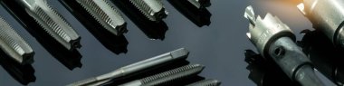 Yakın çekim flüt ucu ve arka planda delik testeresi. Endüstriyel dinleme aletleri. Karpit uçlu metal kesici. Metal işçiliği donanımı. Tamirci aletleri. Sondaj ekipmanları. Makine mühendisliği. 
