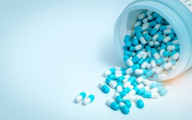 Mavi-beyaz antibiyotik kapsül hapı ve kapsül hapları şişesi. Antibiyotik ilaç direnci. İlaç konsepti. İlaç sanayisi. Eczane ürünü. Kapsül hapları üretimi. Antimikrobik ilaç..