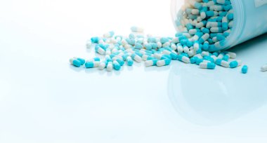Mavi-beyaz antibiyotik kapsül hapı ve kapsül hapları şişesi. Antibiyotik ilaç direnci. İlaç konsepti. İlaç sanayisi. Eczane ürünü. Kapsül hapları üretimi. Antimikrobik ilaç..