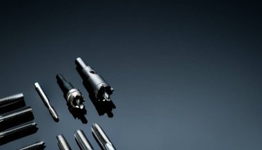 Yakın çekim flüt ucu ve arka planda delik testeresi. Endüstriyel dinleme aletleri. Karpit uçlu metal kesici. Metal işçiliği donanımı. Tamirci aletleri. Sondaj ekipmanları. Makine mühendisliği. 