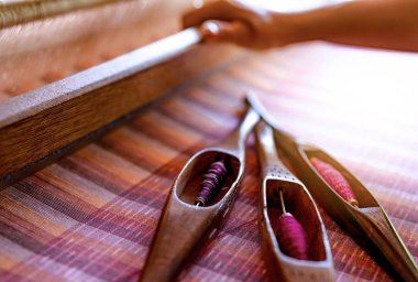 El yapımı kumaş dokuma makinesi üzerinde çalışan bir kadın. Tekstil dokuması. Geleneksel el dokuma tezgahlarını pamuk lifleri üzerinde dokumak. Tayland 'da tekstil ya da kumaş üretimi. Asya kültürü.