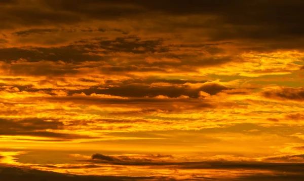 Schöner Himmel bei Sonnenuntergang. Goldener Himmel bei Sonnenuntergang mit schönem Wolkenmuster. Orange, gelb und dunkle Wolken am Abend. Freiheit und ruhiger Hintergrund. Schönheit in der Natur. Mächtige und spirituelle Szene. — Stockfoto