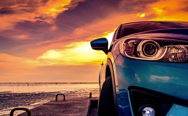 Kék kompakt Suv autó sport és modern design parkolt beton úton a tengerparton naplementekor. A luxusautó elől. Szekrény Suv ködlámpa és fényszórók gyönyörű naplemente ég nyáron. — Stock Fotó