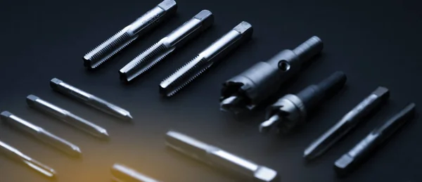 Closeup straight flute tap tip and hole saw on dark background.  Industrial tapping tools. Carbide tip metal cutter. Metalworking hardware. Mechanic tools. Drilling equipment. Mechanical engineering. — 스톡 사진