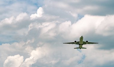 Mavi gökyüzünde uçan ticari havayolu şirketi ve beyaz tüylü bulutlar. Uçağın uçuşu gözönüne alındığında. Kalkıştan sonraki yolcu uçağı ya da iniş uçuşu. Tatil seyahati. Hava taşımacılığı.