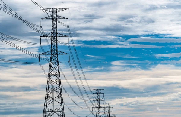 Hoogspanning elektrische pyloon en elektrische draad met blauwe lucht en witte wolken. Grote elektriciteitspaal. Energie- en energieconcept. Hoogspanningsnettoren met draadkabel bij distributiestation. — Stockfoto