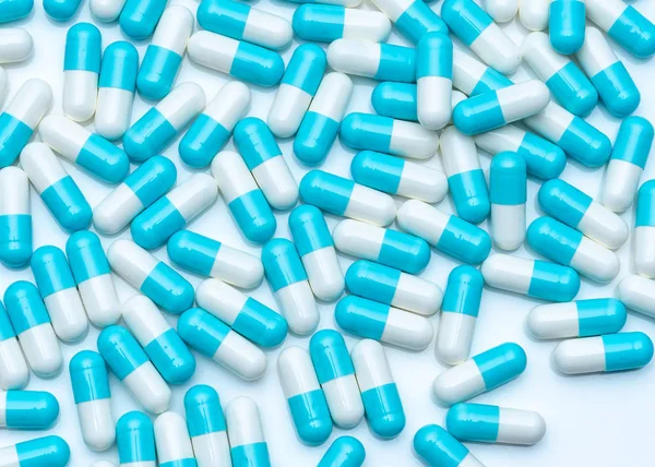 Pillole capsule blu-bianche sul tavolo bianco. Quadro completo di pillole di droga capsula. Prodotto farmaceutico. Concetto di produzione farmaceutica. Farmaceutica. Uso di medicinali in ospedali e farmacie. Sanità pubblica . — Foto Stock