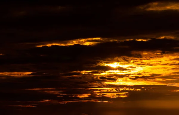 Hermoso cielo al atardecer. Cielo dorado al atardecer con hermoso patrón de nubes. Nubes anaranjadas, amarillas y oscuras por la noche. Libertad y calma de fondo. Belleza en la naturaleza. Escena poderosa y espiritual. — Foto de Stock