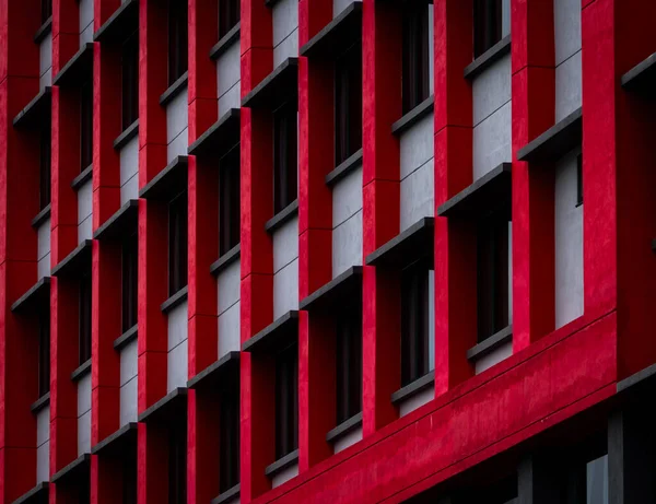 Glass window of skyscraper office building with red and white concrete wall. Exterior commercial building. Modern architecture design. Facade of modern business building. Concrete and glass building.