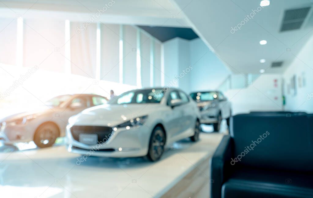 Blurred front view of white car and customer. New luxury car parked in modern showroom. Car dealership office. Electric car business concept. Automobile leasing. Showroom interior building design.