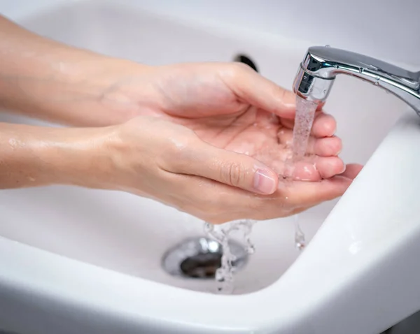 妇女在浴室用自来水洗手 为个人卫生起见 手在水龙头下洗干净 第一步是清洁肮脏的手 以防止流感和头孢病毒 洗手的好程序 — 图库照片
