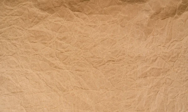 Old wrinkled brown paper texture background. Rough brown kraft paper texture. Recycle cardboard sheet. Rustic background pattern design. Closeup crumpled paper bag. Grunge and creased parchment.