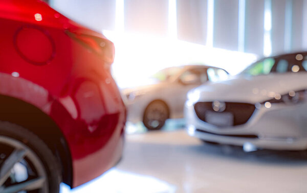 Blurred of white and red luxury car parked in modern showroom. Car dealership office. Electric car business concept. Automobile leasing. Automotive industry crisis background concept. Shiny car.