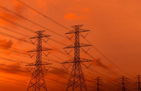 High voltage electric pylon and electrical wire with sunset sky. Electricity poles. Power and energy concept. High voltage grid tower with wire cable. Beautiful red-orange sunset sky. Infrastructure.