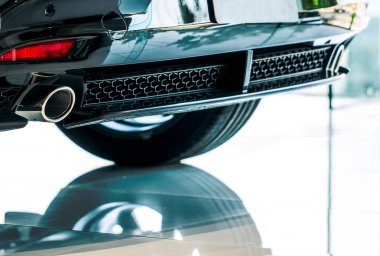 Yakından bakınca, galeriye park etmiş arabanın egzoz borusunu yansıtıyor. Araba egzoz borusunun eşsiz deseni. Spor araba için aksesuarlar. Benzinli araba egzoz borusu. Otomobil arka ızgarası.