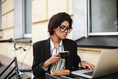 Elinde kahve ile kafeterya masada oturan gözlüklü Afro-Amerikan kız portresi