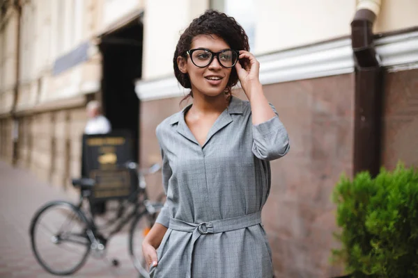 Krásná africká americká dívka v brýlích, stojící na ulici a zasněně dívá stranou — Stock fotografie