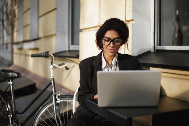 Kafeterya masada oturan ve onu laptop çalışma gözlüklü Afro-Amerikan kız portresi